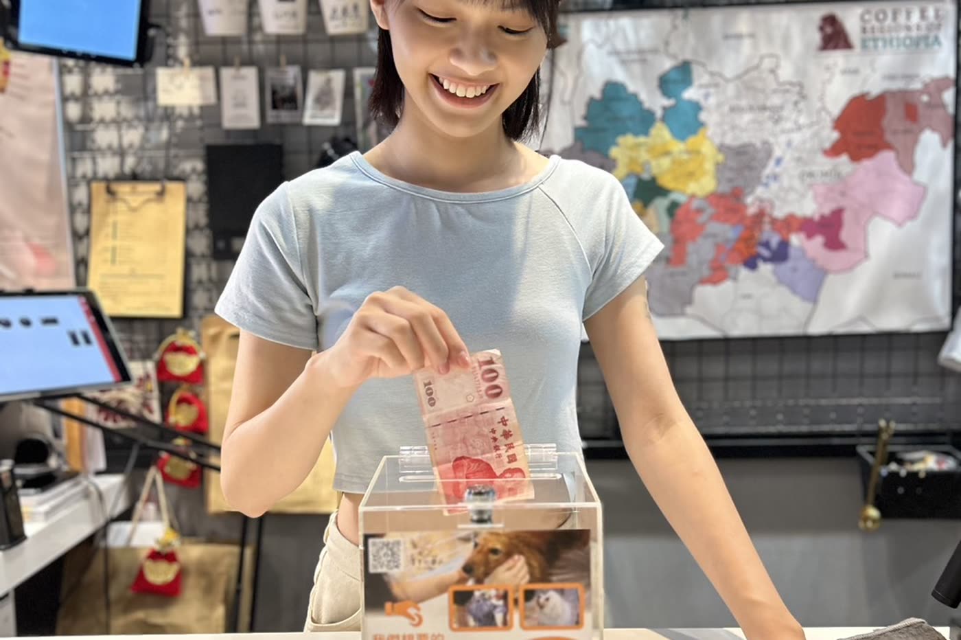 民眾在店家櫃檯將紙鈔投入協會的愛心捐款箱